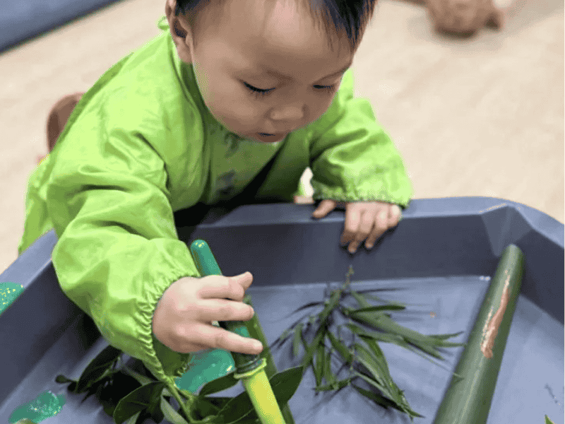 A small child nature painting at activity table.