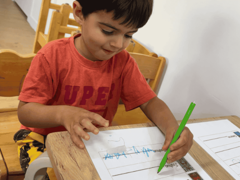 Preschool child sitting at table writing name