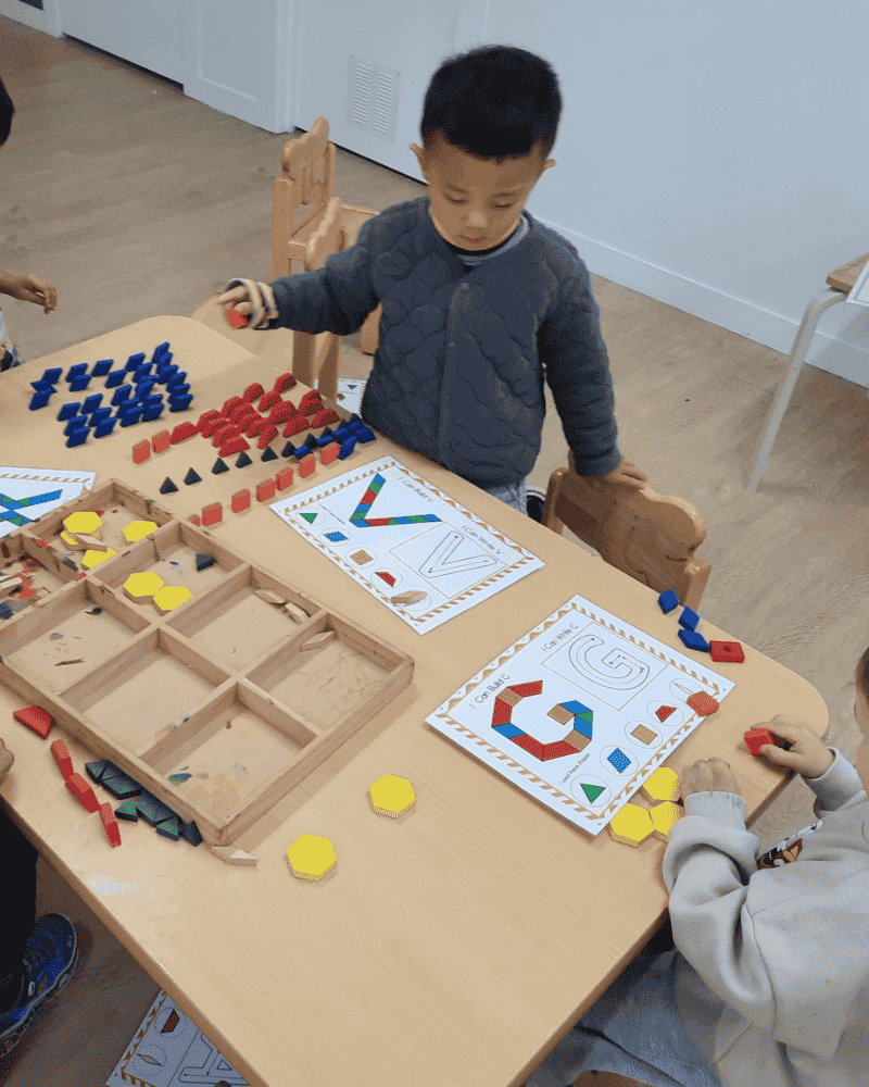 A preschool child learning through play with coloured shapes and letters indoors